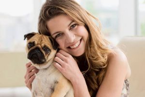 Smiling-woman-holding-cute-small-dog-on-lap